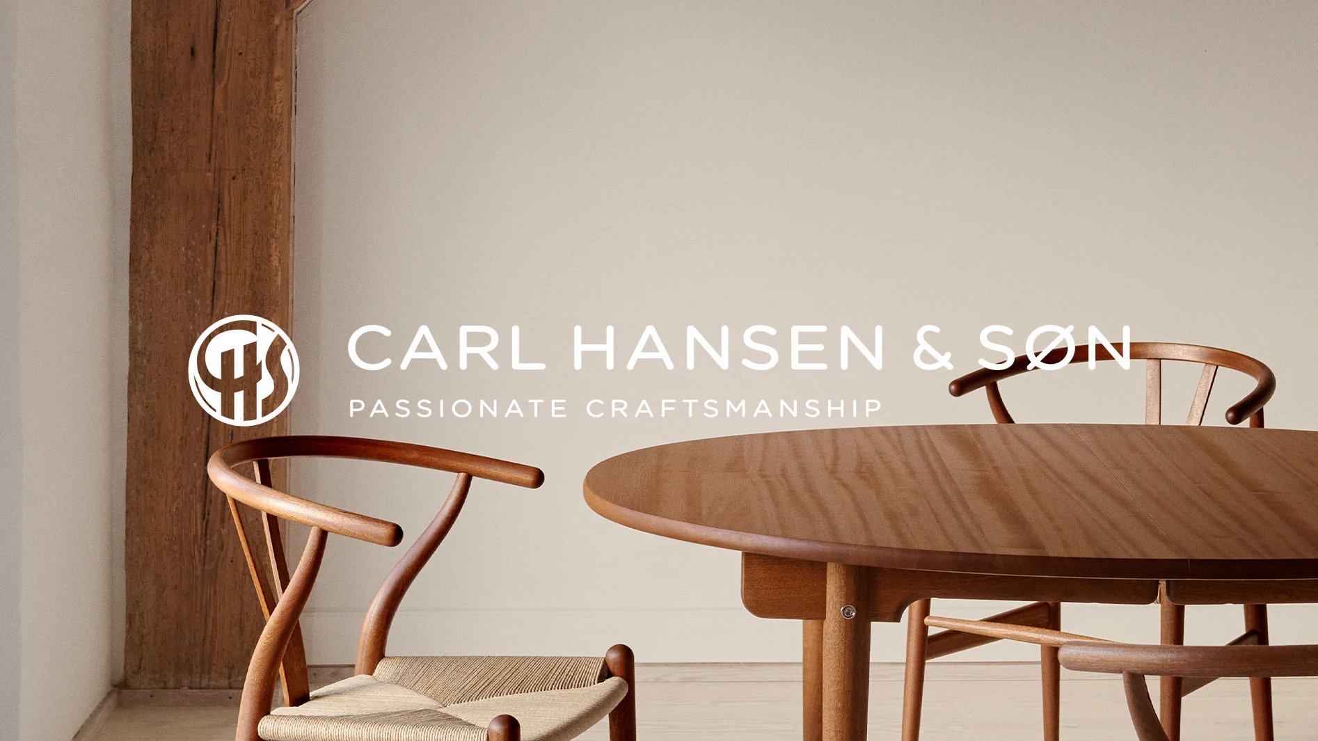 Runt träbord med två stolar i ljust trä och flätad sits, Carl Hansen & Søn logga och text Passionate Craftsmanship.