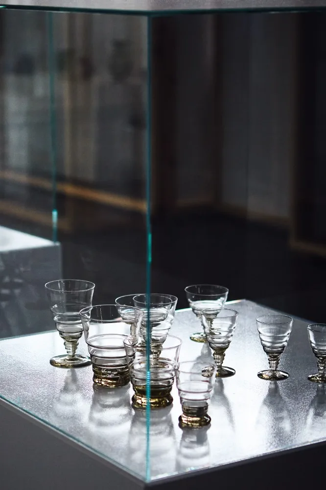 Flera tomma dricksglas med räfflad design och gulaktiga baser i en glasmonter.