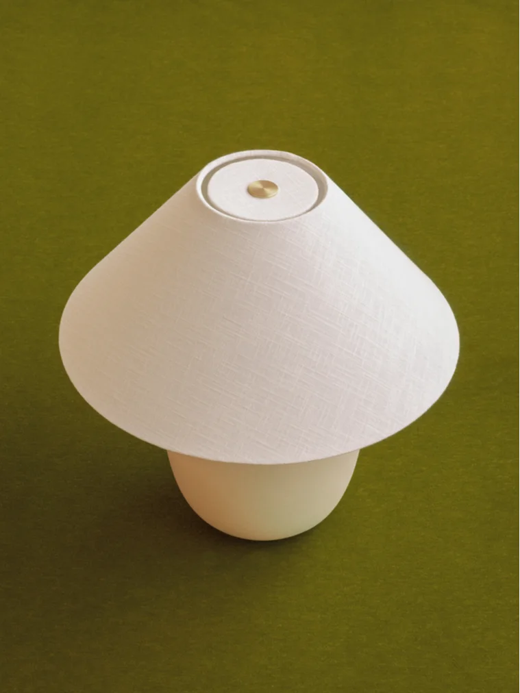Svampformad bordslampa med vit tygskärm och ljus fot, med en mässingsdetalj på toppen.