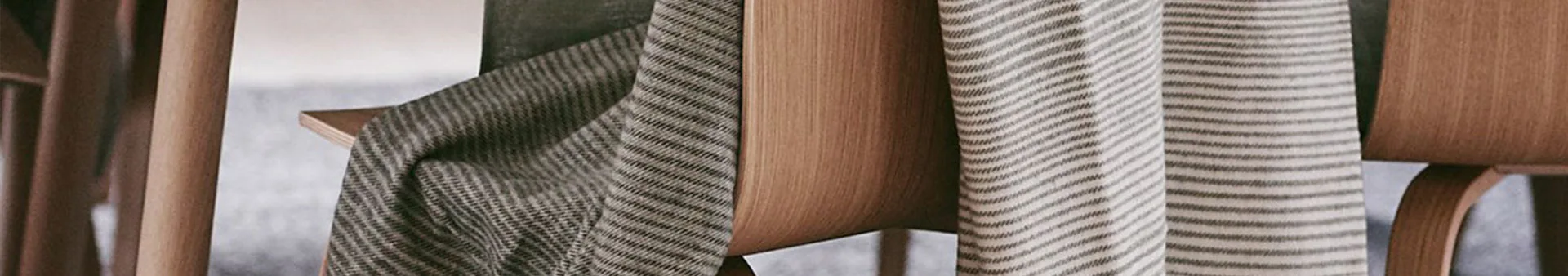 Närbild av en beige och svartrandig textil draperad över varmt trä.