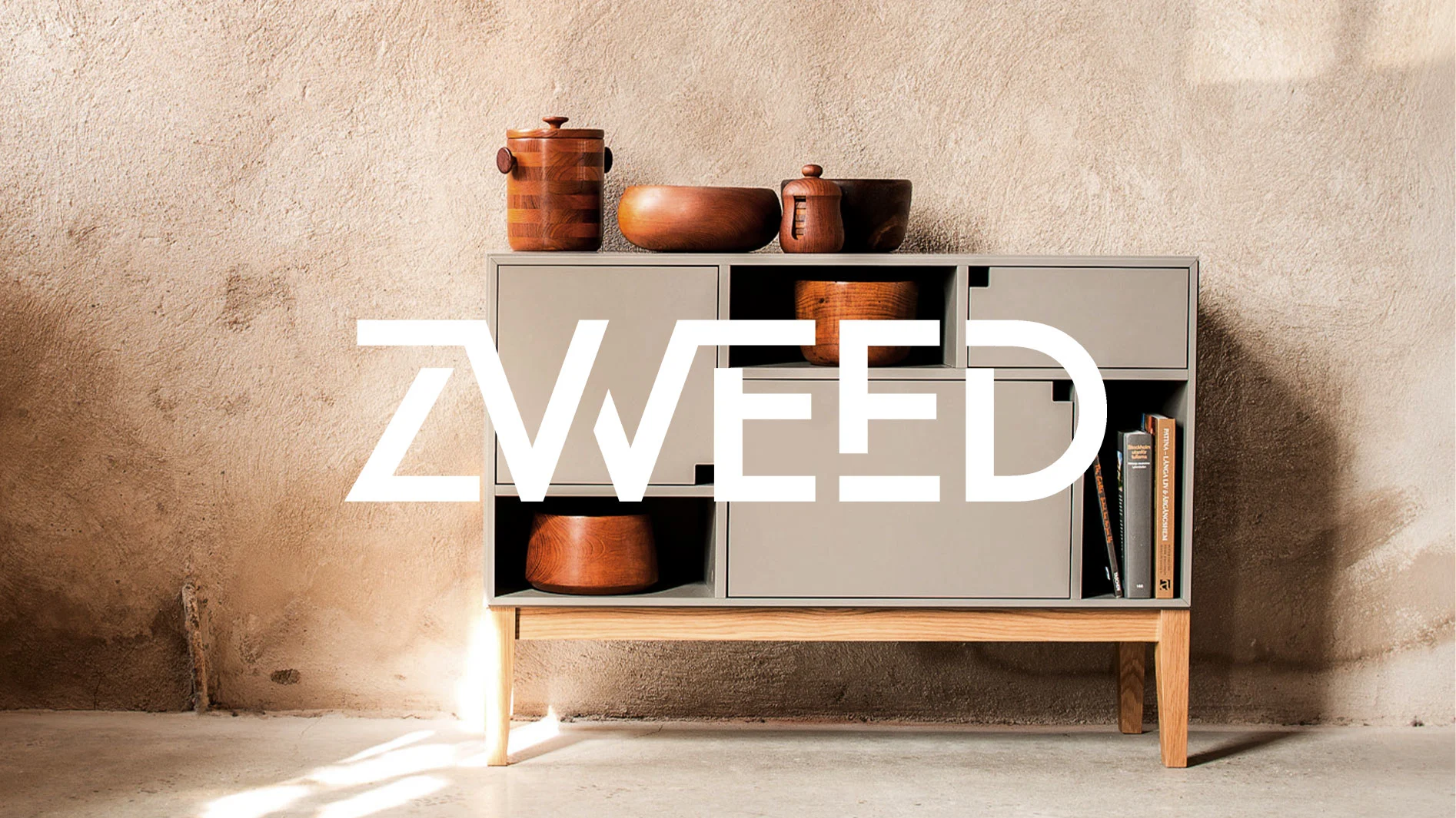 ZWEED-logotyp över ett ljusgrått och träfärgat skåp med olika träskålar och böcker, mot en texturerad vägg.