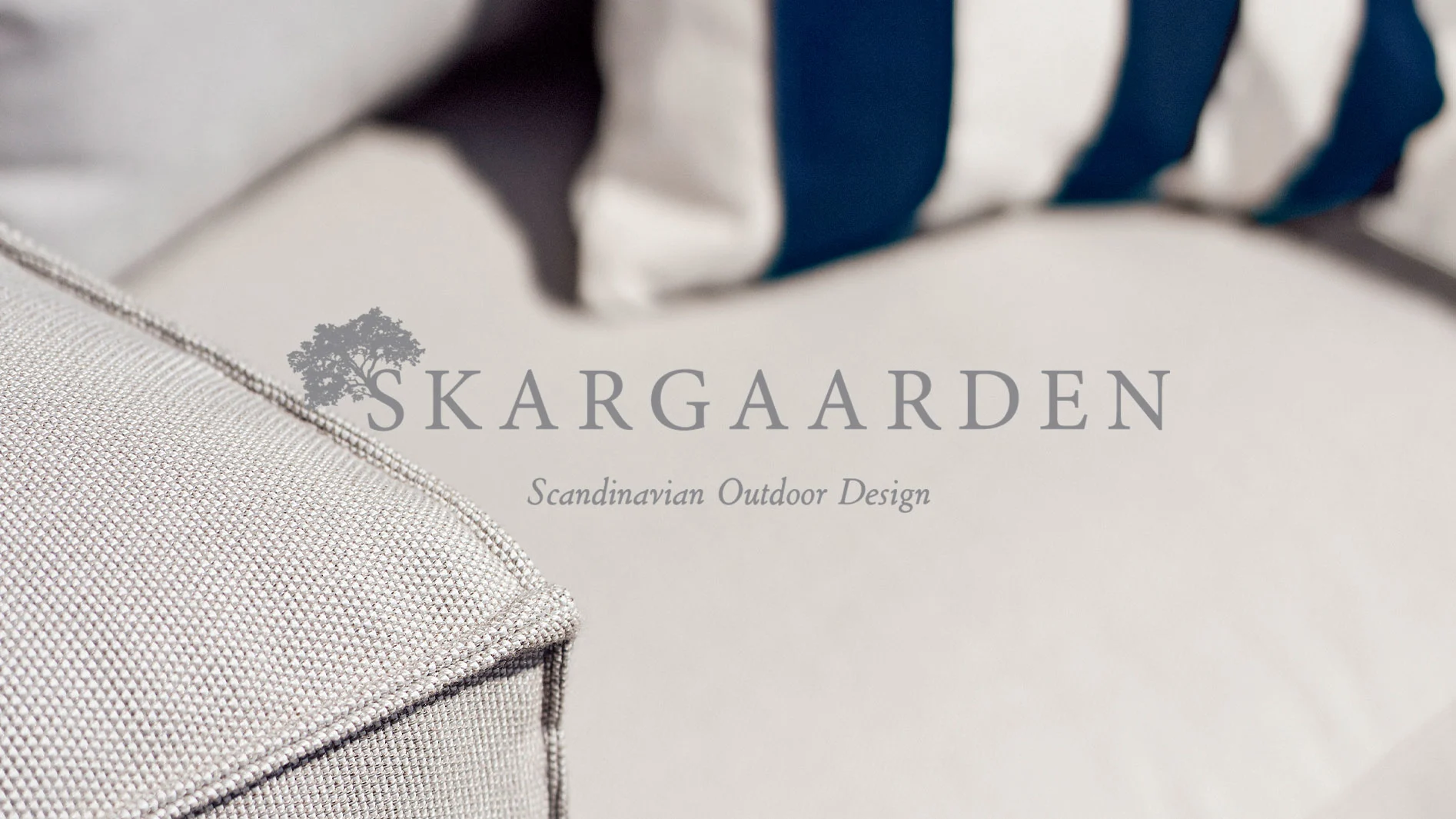 Närbild av ljusgrå utomhuskuddar med en blå- och vitrandig kudde i bakgrunden och Skargaarden-logotypen.