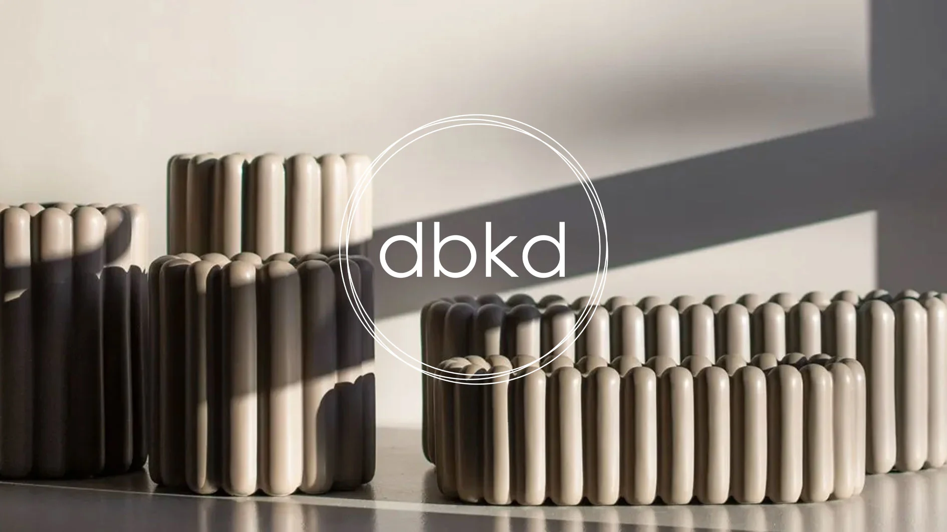 Flera ribbade, beige/ljusbruna krukor i olika storlekar med dbkd-logotyp.