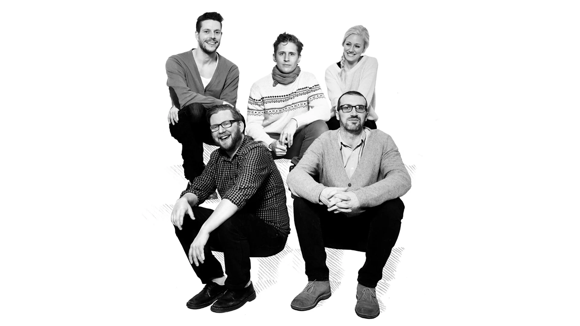 Gruppbild av fem leende personer, tre män och två kvinnor, ledigt klädda mot en vit bakgrund.