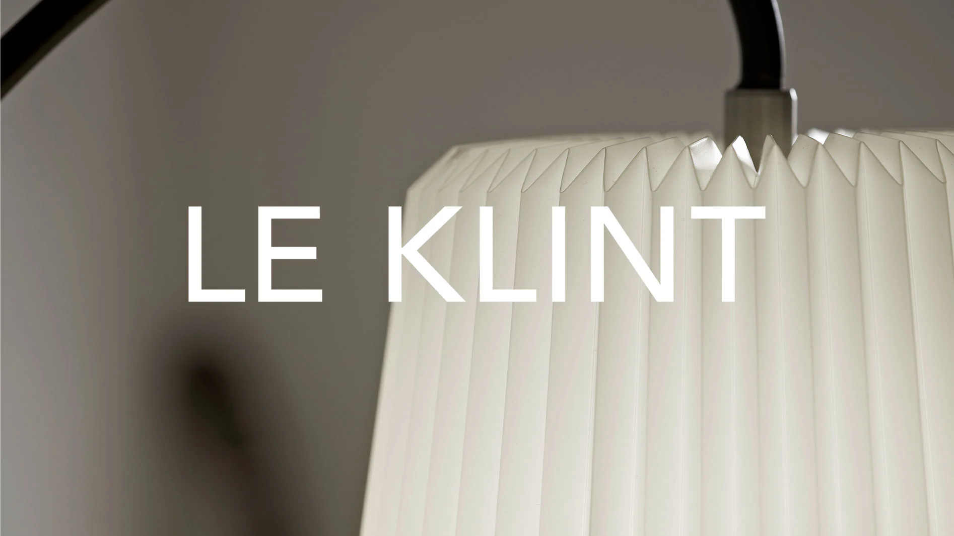 Vit veckad lampskärm med varumärket LE KLINT i stora vita bokstäver.