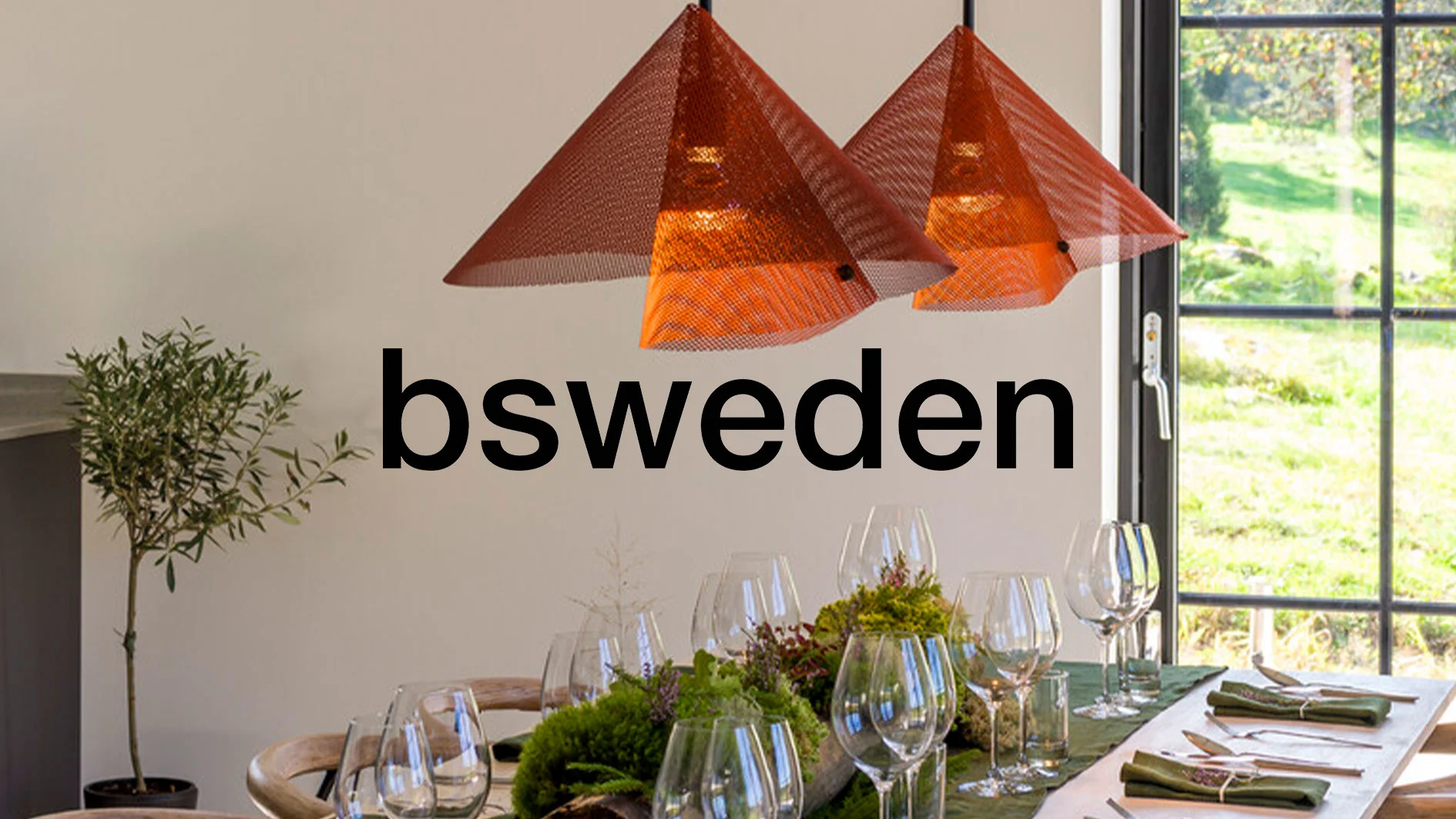 Matbord med vinglas, gröna servetter, två orange pyramidformade taklampor, och en logotyp som säger 'bsweden'.