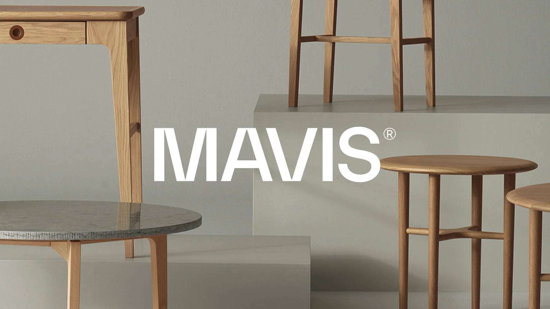 MAVIS-logotyp framför ett urval moderna trämöbler: ett skrivbord, ett runt bord med stenskiva, en barstol och två runda sidobord.