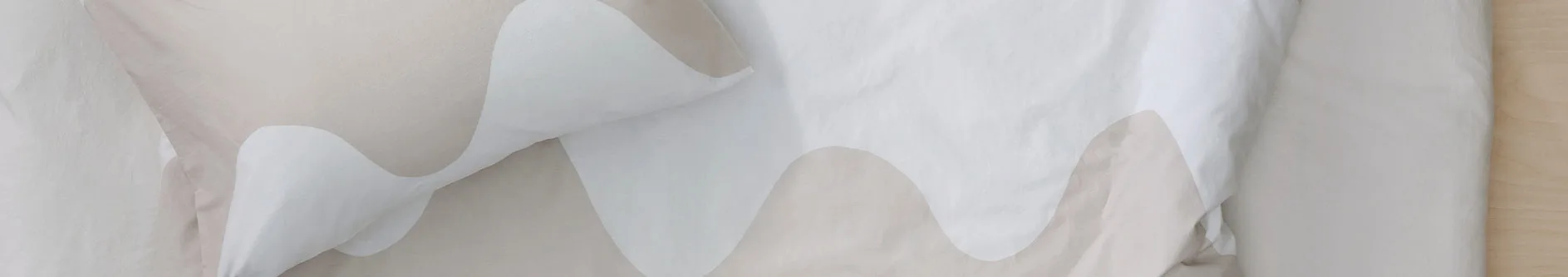 Sängkläder med vågigt mönster i vitt och beige.