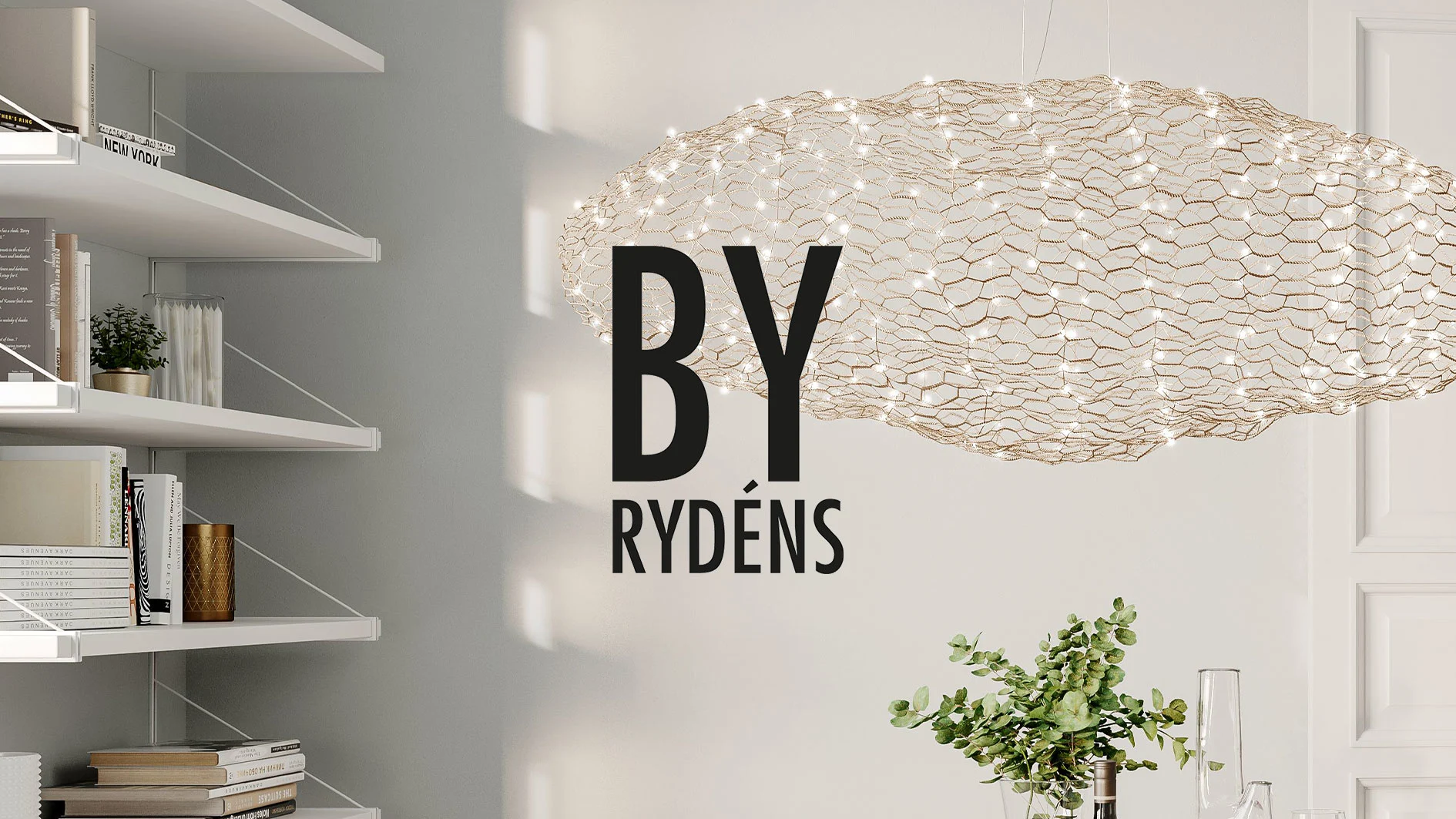 By Rydéns logotyp framför en lysande, molnformad ljuskrona i ett rum med vita hyllor och växter.